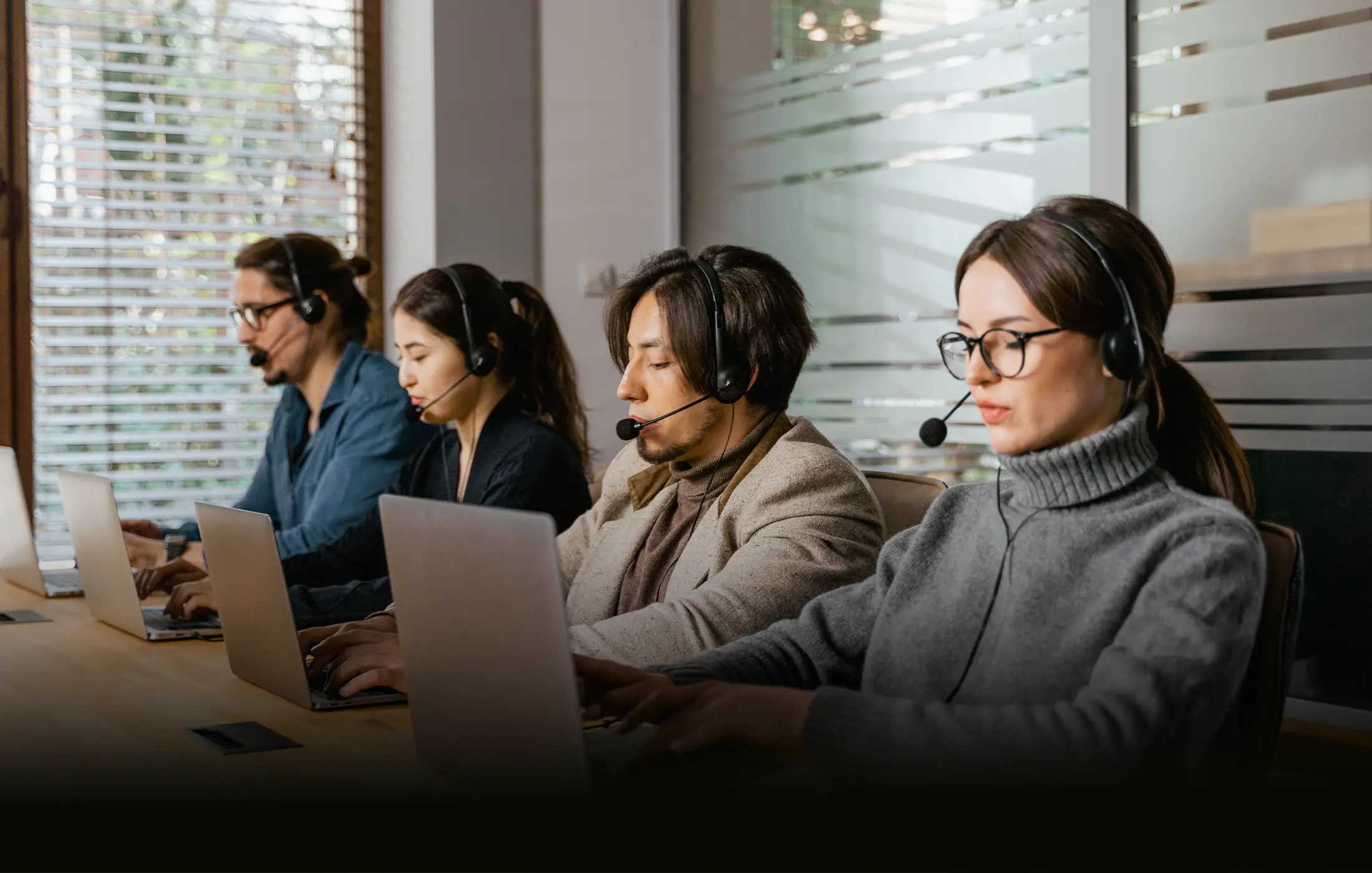A customer-support team working at laptops while wearing headsets.