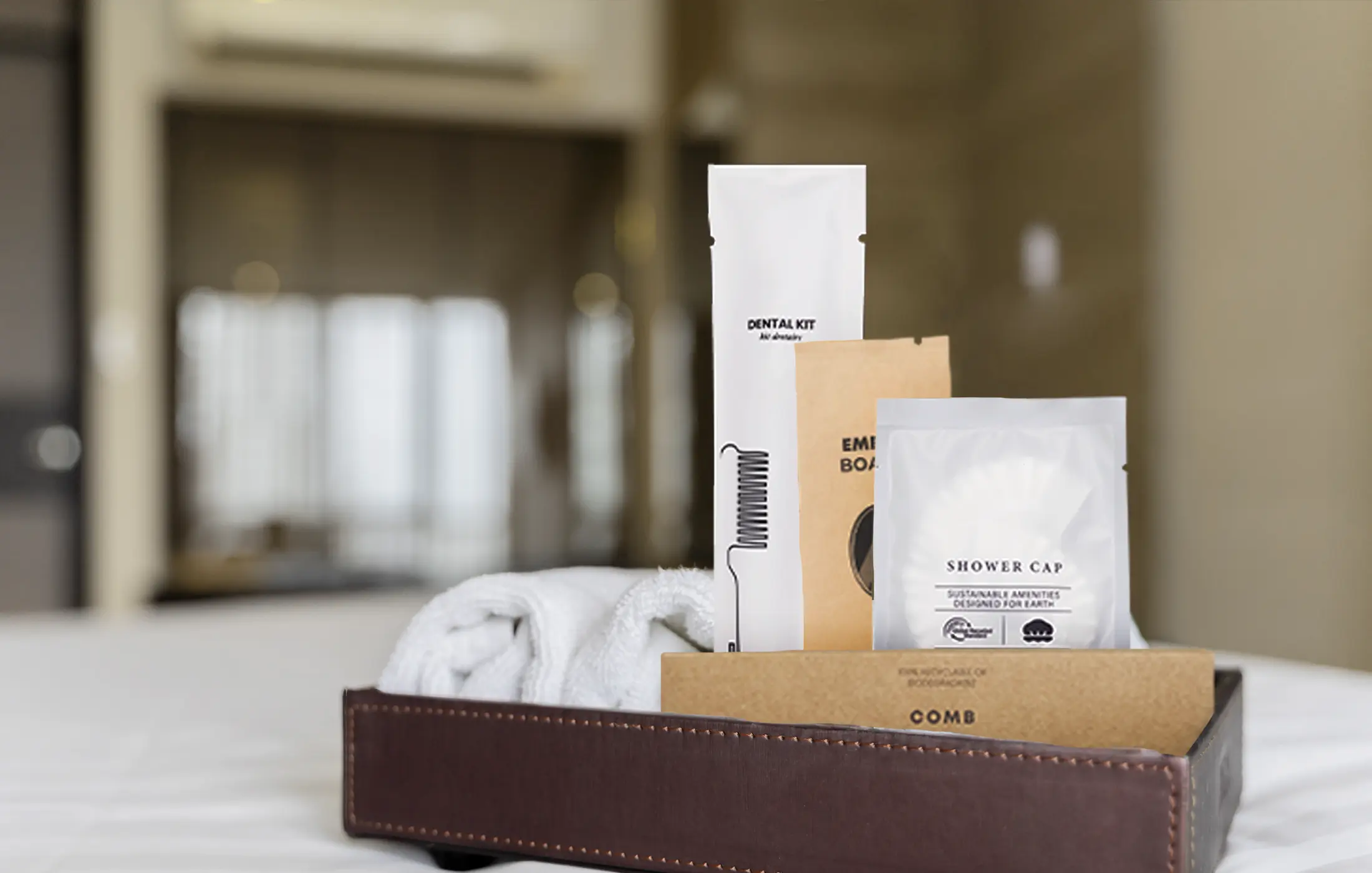 Dry amenity kits arranged beside rolled towels in a hotel bathroom.