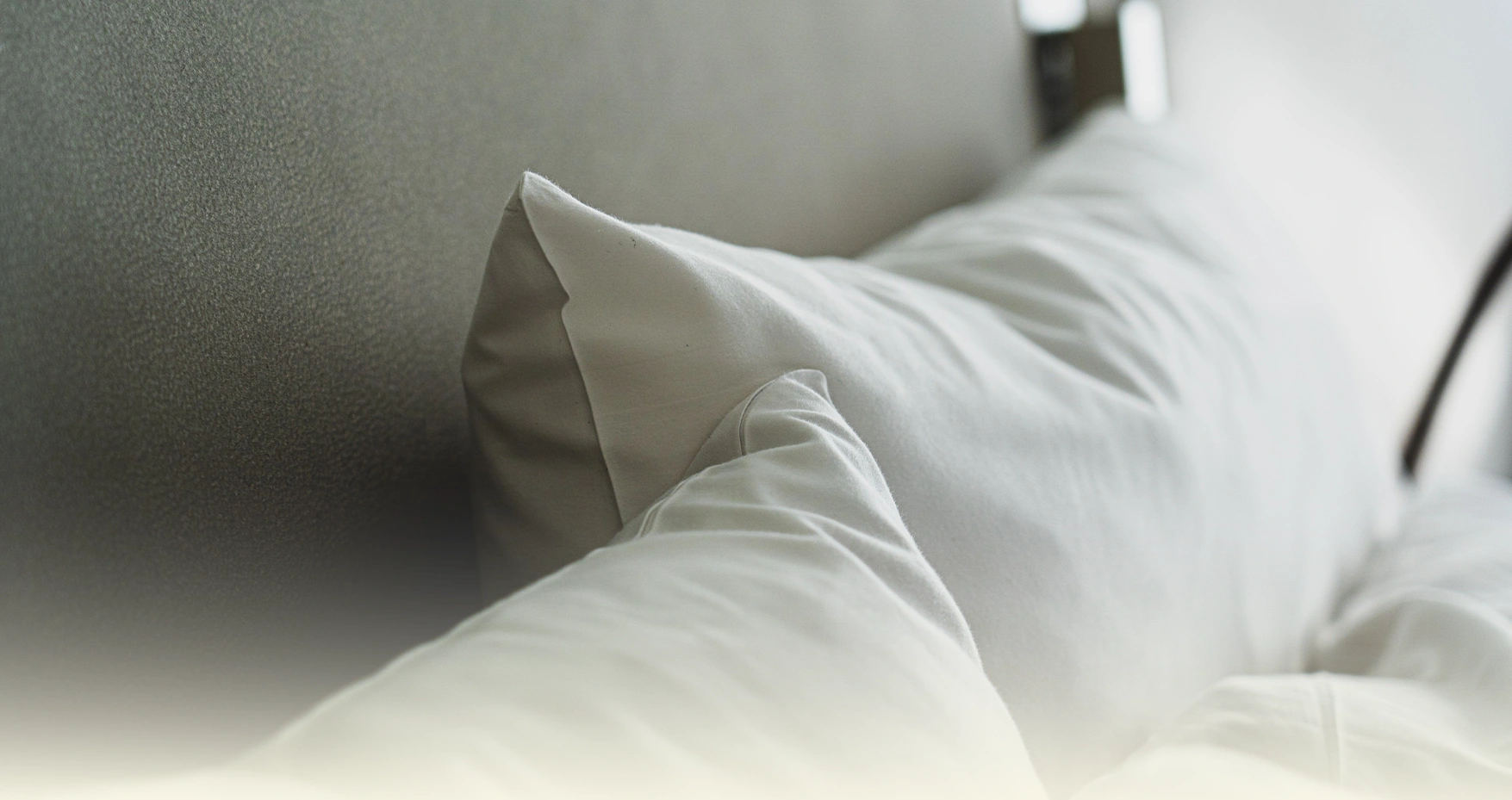 Layered white hotel pillows in soft natural light.